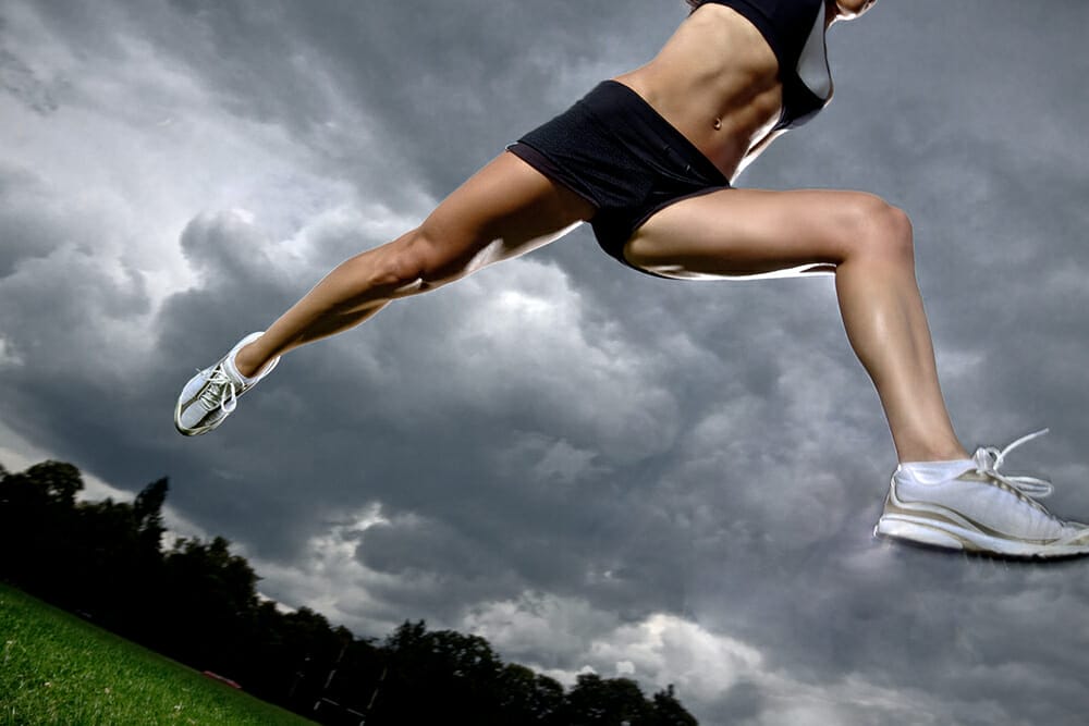 photograph of woman jumping over hurdle in storm