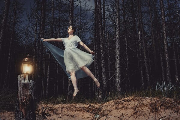 model floating in the woods with little lantern lighting the dark