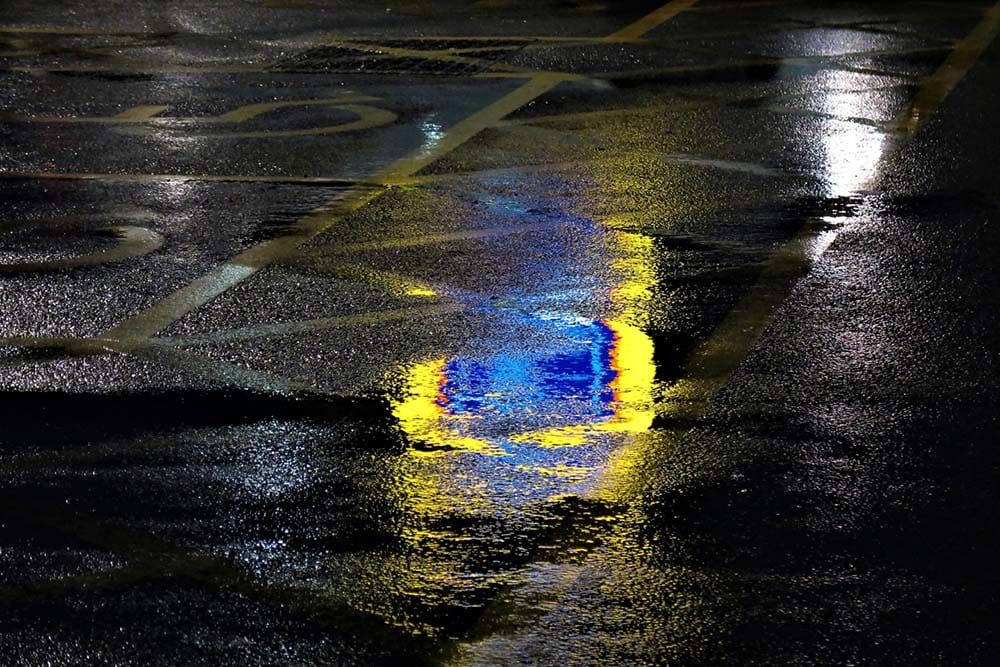 reflections of a supermarket sign in a puddle at night
