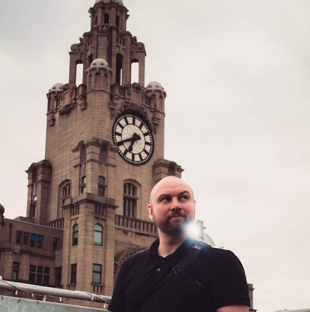 a wedding photographer standing infront of the liver buildings