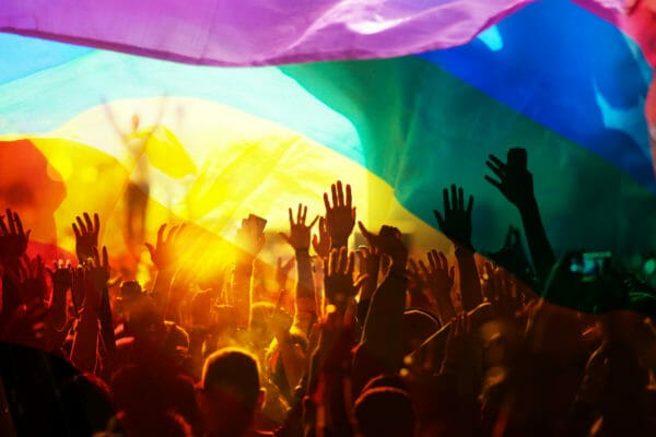 pride flag over a non socially distanced crowd LGBTQ+ photography