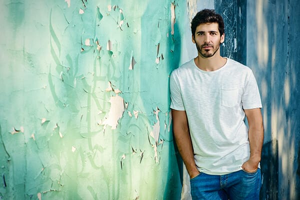 posing men blog image man leaning against a wall paper distressed in white tshirt and jeans