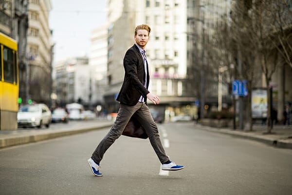 posing men blog image man walking acorss the street holding a bag