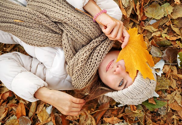 overhead fall photo of lady lying down face covered by leaf