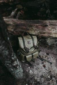 how to do product photography Camera bag next to a fallen tree trunk muted green colour