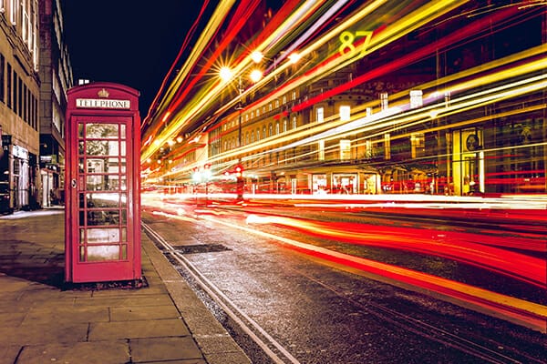 light trails of a london bus passing a red phone box at night