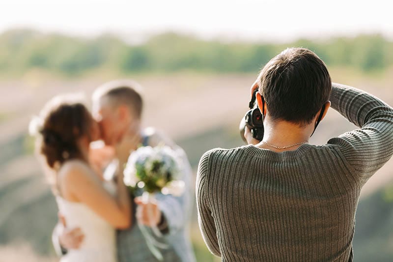 a wedding photographer taking a photo of a bride and groom