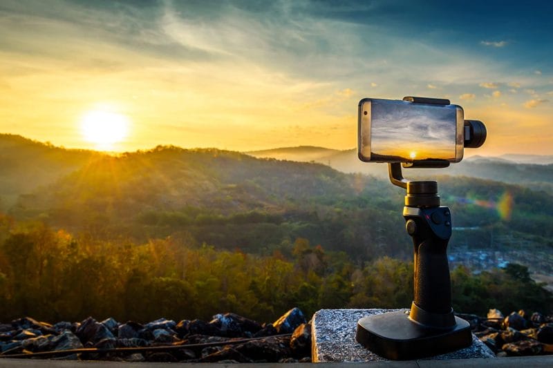 Close-up Smartphone take a Mountains Landscape photo and video timelapse on stand Mobile Stabilizer in sunset