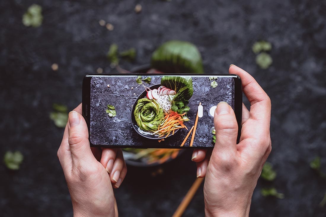 Photographing food. Hands taking picture of delicious vegetable salad with smartphone