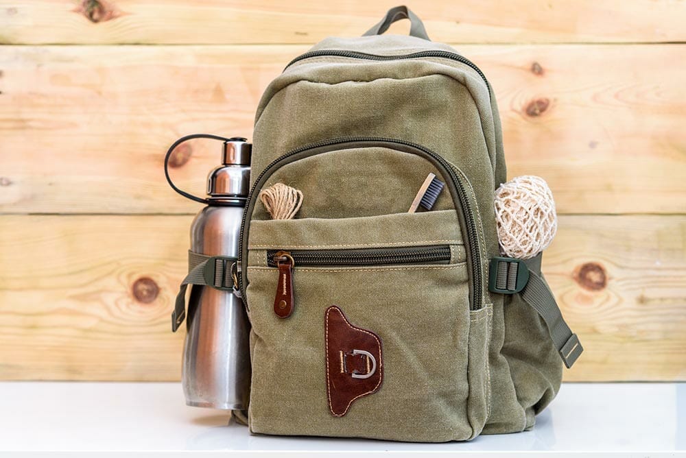 Zero waste travel. Backpack with stainless steel plastic free reusable water bottle, natural reusable cotton mesh grocery bag, eco-friendly bamboo toothbrush, rope natural twine hemp linen cord.
