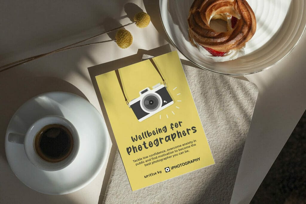Wellbeing for Photographers Book on a table in between a coffee cup and pastry