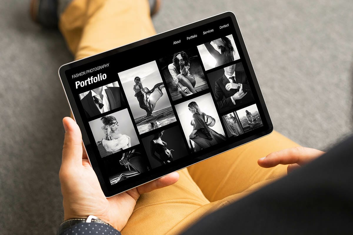 Man viewing black and white fashion photography portfolio website on tablet computer