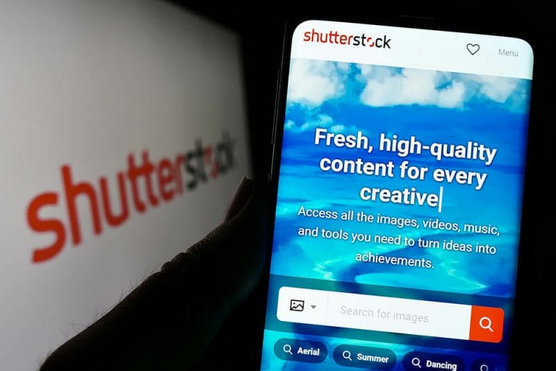 Stuttgart, Germany - 01-08-2023: Person holding cellphone with website of US stock photography company Shutterstock Inc. on screen with logo. Focus on center of phone display. Unmodified photo.