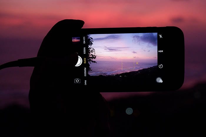 woman taking a photo of dusk beach in low light