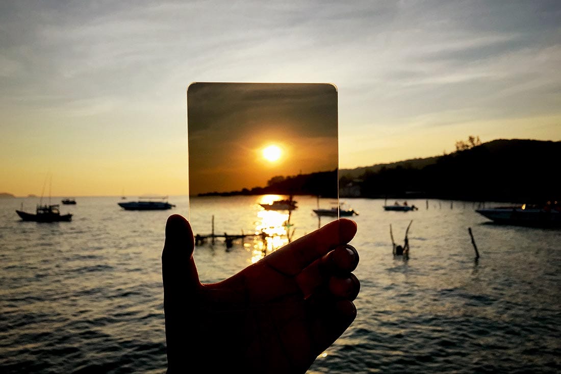Silhouette hand on hard nd filter with sunrise for photograph technic in sea and ocean