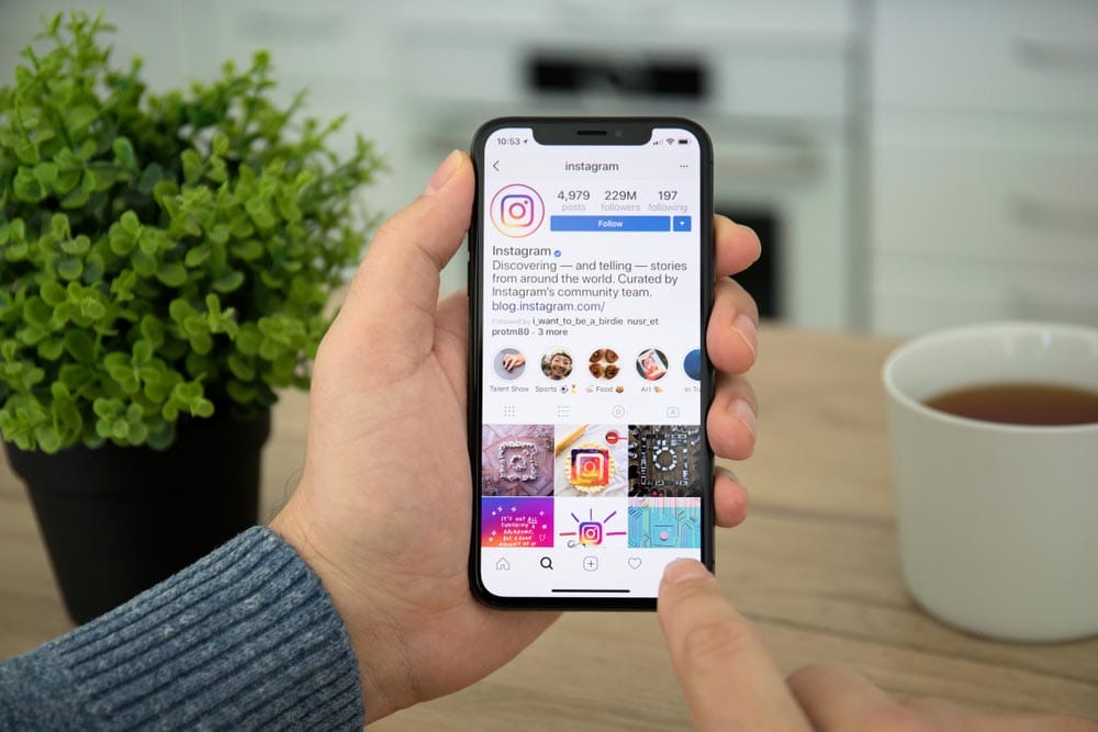 Man hand holding iPhone X with social networking service Instagram on the screen. iPhone 10 was created and developed by the Apple inc.