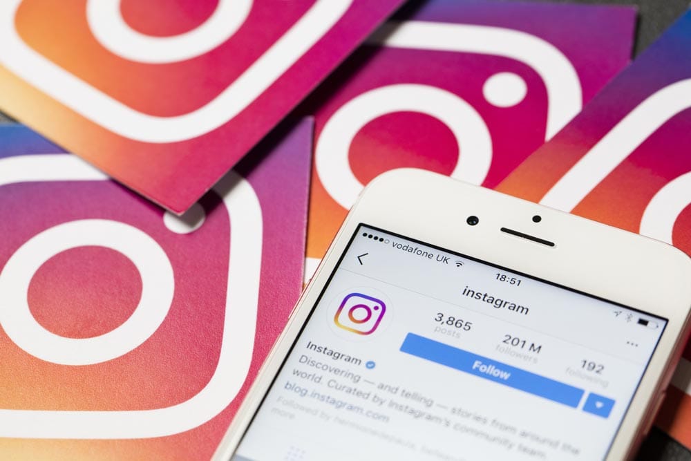 An apple iPhone showing the instagram application alongside other instagram printed logos. Instagram is a popular social media application for sharing images and videos