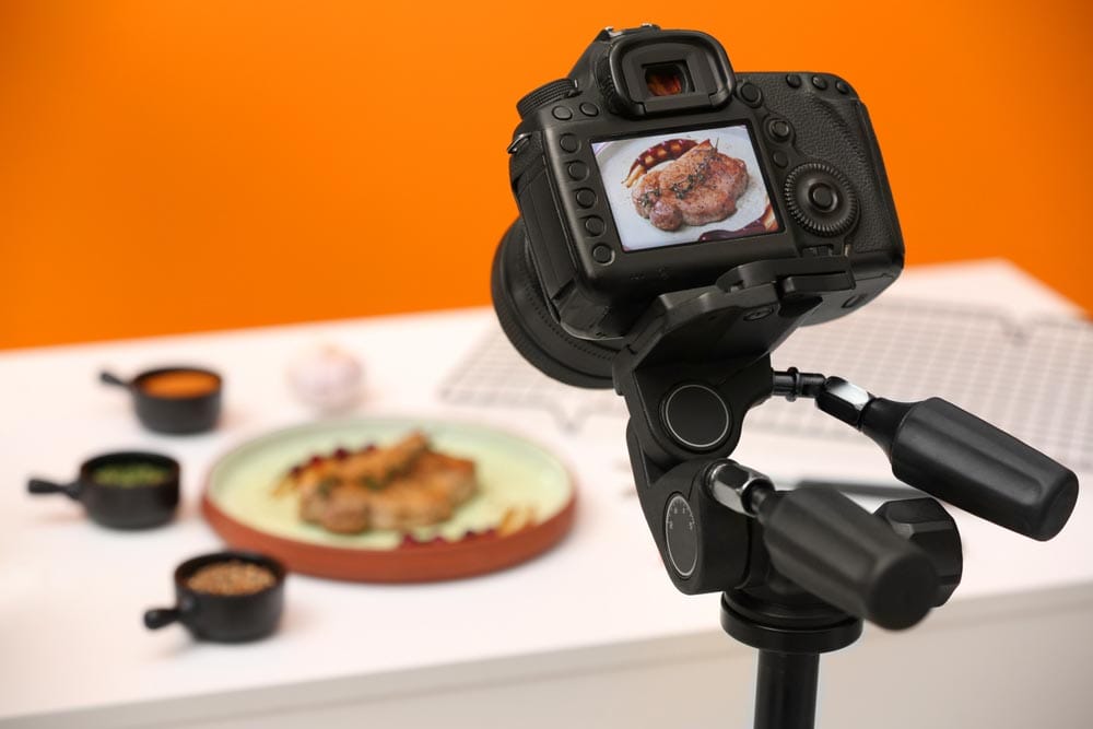 Professional camera with picture of meat medallion on display in studio, space for text. Food stylist