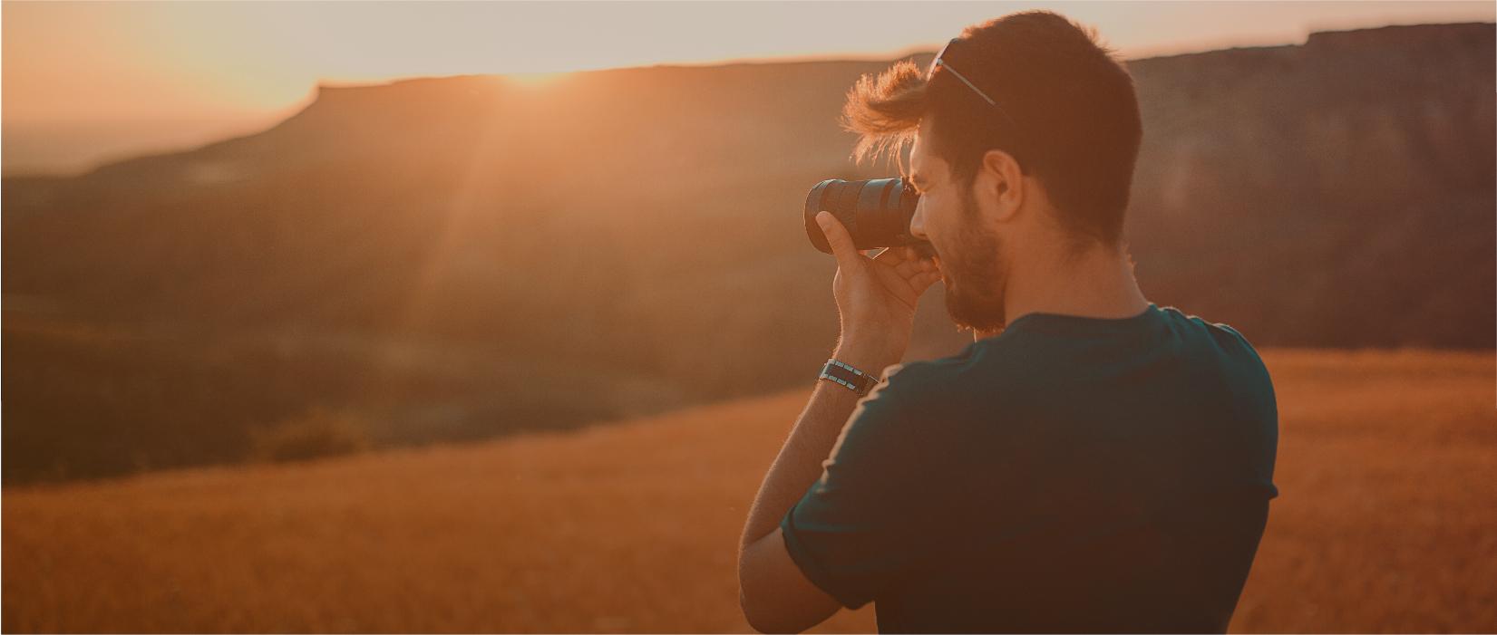 Man taking a photo of a landscape at sunset