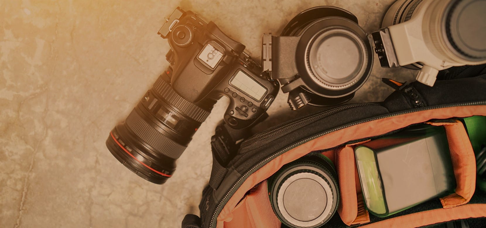 an overhead view of a digital camera and lenses next to camera bag