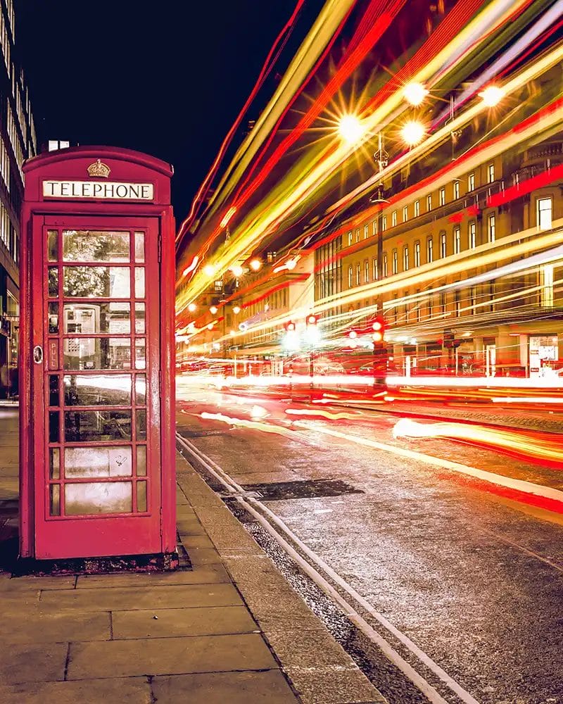 light trails of a London bus passing a red london phone box at night