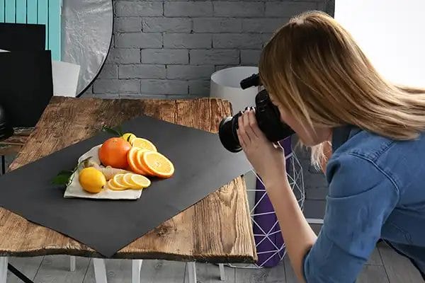 a female food photographer taking photos of fruit on a kitchen table
