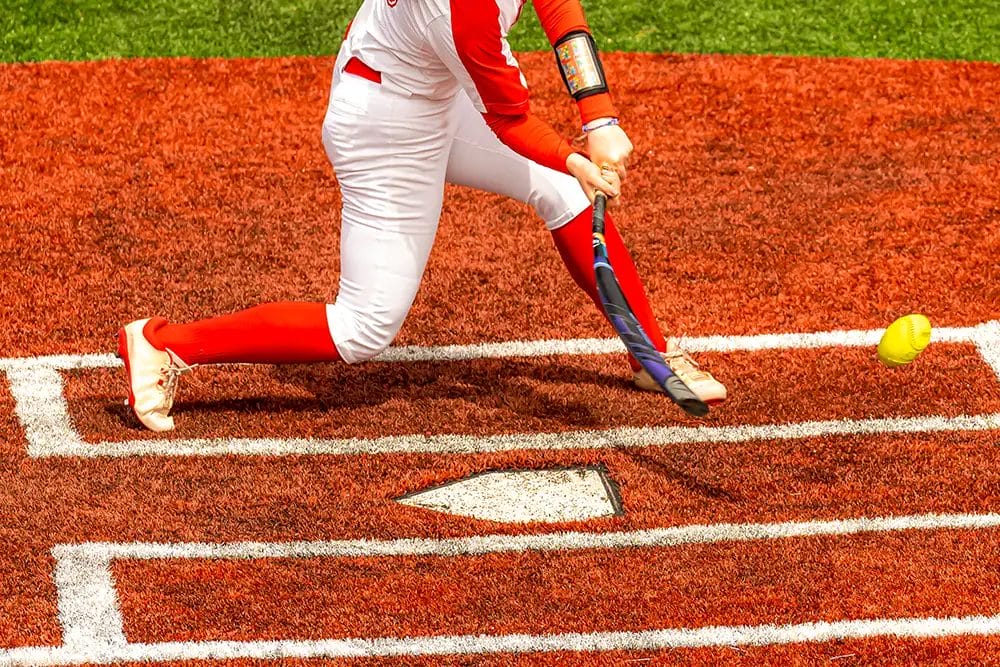 A baseball player hitting a ball but the bat looks bent