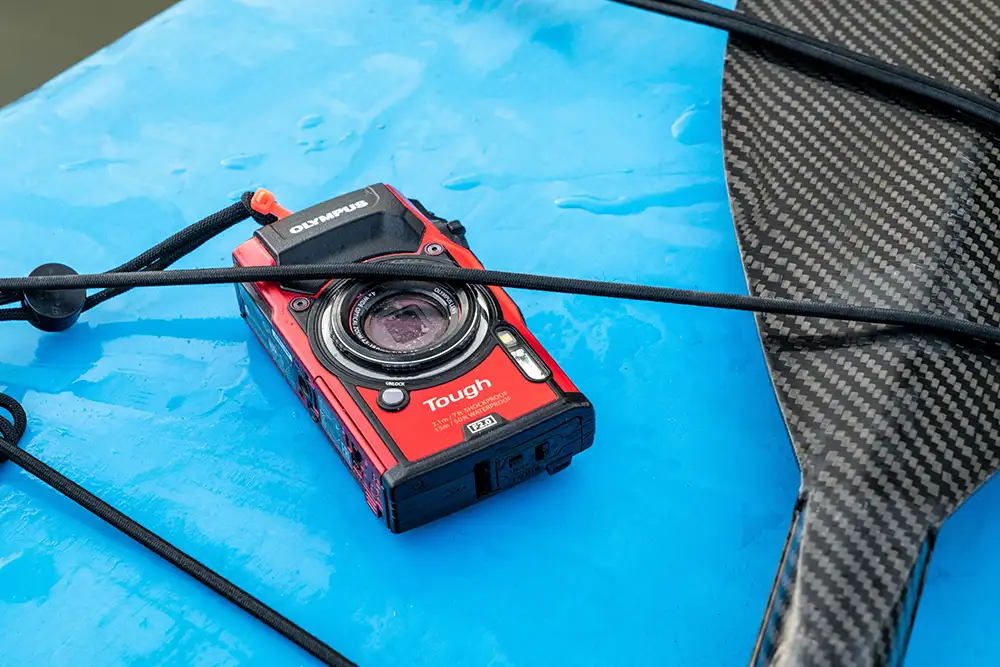 Image of a red Olympus Tough TG-6 camera strapped down to a blue surfboard