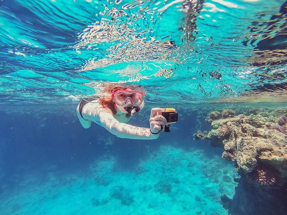 lady underwater holding a gopro camera