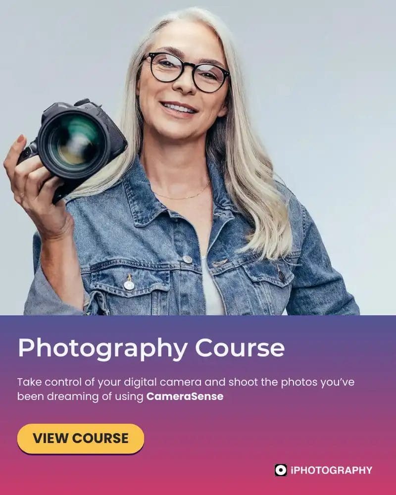 a woman with long white hair with a denim jacket holding a digital camera