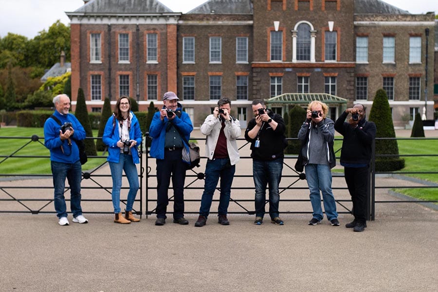 group of photographers holding cameras to their faces stood in front of Kensington Palace in London