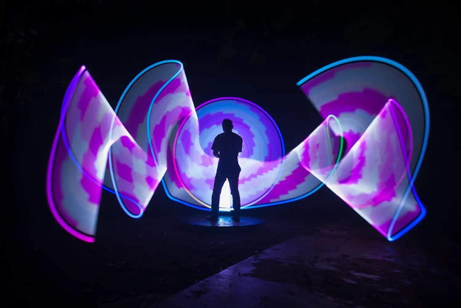 A man holding an RGB LED pixelstick creating a blue and purple light painting