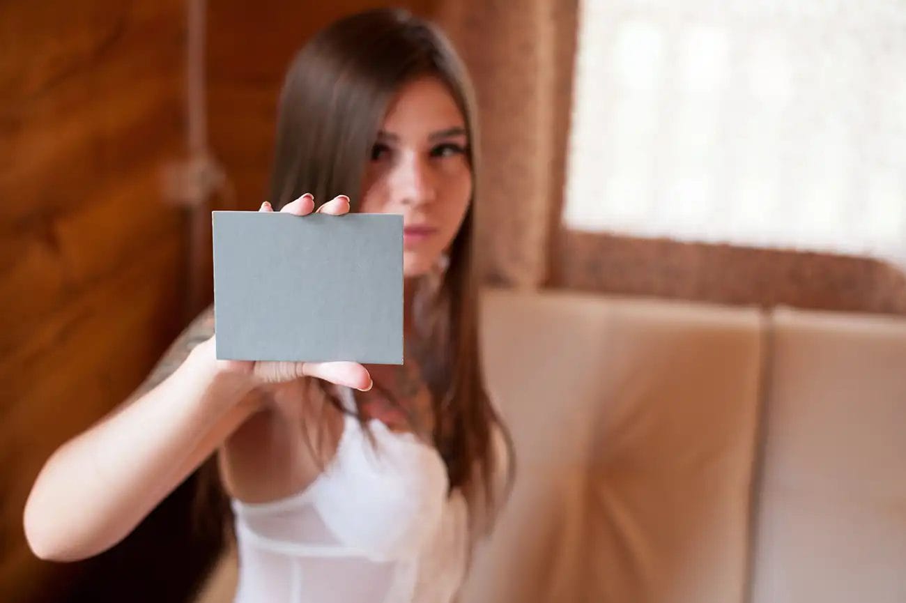 A woman holding up a grey card to face the camera