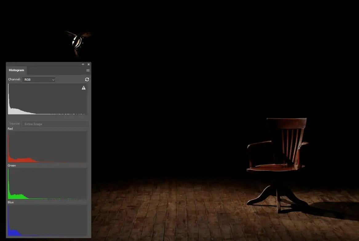 A dark room with a lamp lighting a wooden chair on a wooden floor